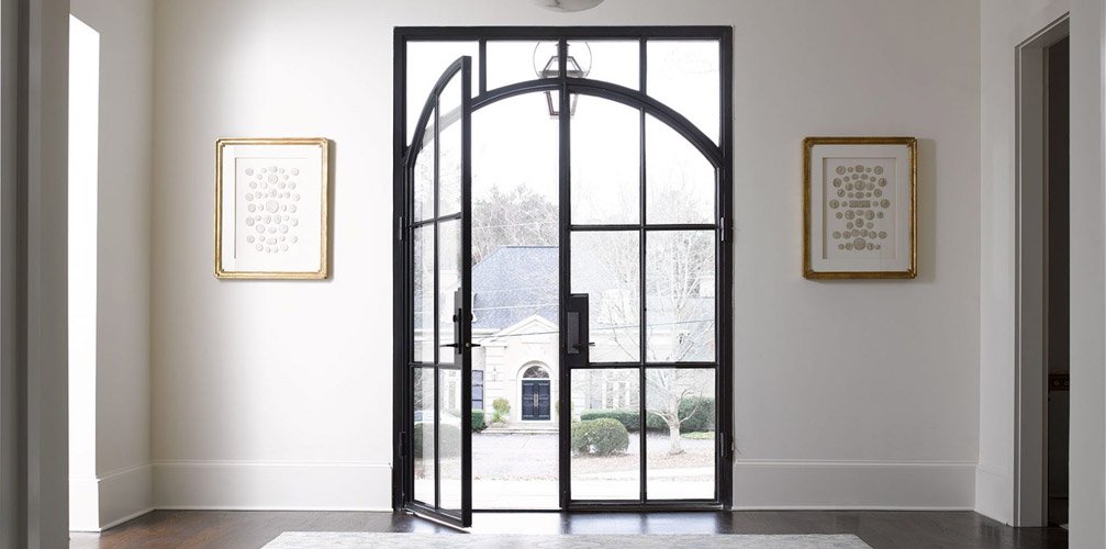 french steel entryway glass steel doors open into hardwood floors white walls gold framed photos